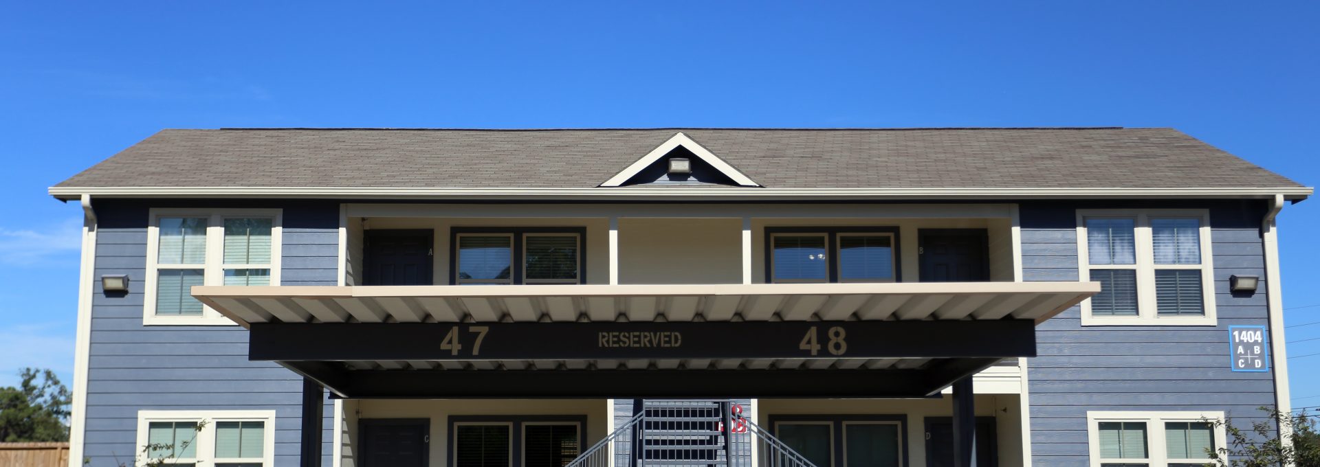 the front of a two story apartment building with a covered parking lot at The Wilson Place 