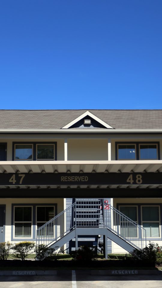 the front of a two story apartment building with a covered parking lot at The Wilson Place 