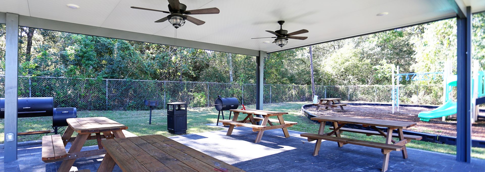 a covered patio with picnic tables and a ceiling fan at The Wilson Place 