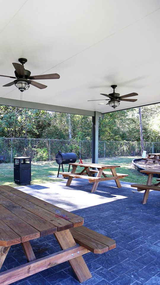 a covered patio with picnic tables and a ceiling fan at The Wilson Place 